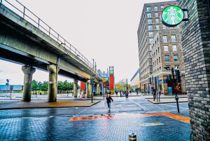 a person walking down a city street with a clock at Luxe 2 Bed Flat - Gallions Reach in North Woolwich