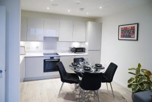 a kitchen with a table and chairs in a room at Luxe 2 Bed Flat - Gallions Reach in North Woolwich