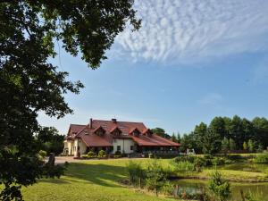 a house with a red roof on a green lawn at Dębowa Dolina in Skuszew