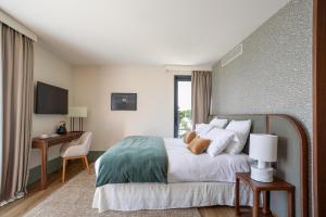 a bedroom with a large bed with a desk and a window at Maison du Lac Boutique Hôtel in Nyon
