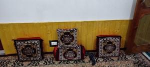 three cushioneditures sitting next to a wall at Mir guest house in Tangmarg