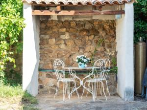 a table and chairs in front of a stone wall at Cosy villa in Montouliers with private pool in Montouliers