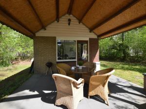 een patio met rieten stoelen en een tafel bij Romantic Forest Retreat with Sauna in Stramproy