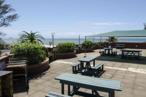 a group of picnic tables on a patio overlooking the ocean at Umdloti Holiday Resort 607 in Umdloti