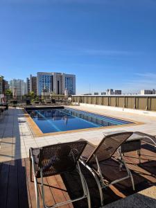 una piscina con 2 sillas en la azotea en Quarto 5 estrelas no Comfort Suites!, en Brasilia