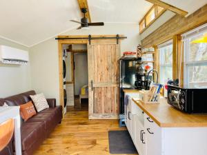 a kitchen and living room with a couch in a tiny house at Misty Hollow Tiny Home Cottage in Robbinsville