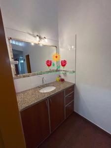 Un baño con lavabo y un espejo grande. en Apartamentos Las Flores, en Villa Carlos Paz
