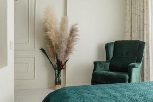 a bedroom with a chair and a vase with feathers at 4You apartments 2 in Almaty