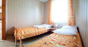 two beds in a small room with a window at OW NaFali in Jarosławiec