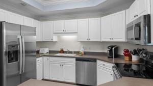 a kitchen with white cabinets and a stainless steel refrigerator at Enjoy a 3-bedroom Bayfront Condo with Lazy River Indoor Pool Jacuzzis and Community Boat Dock for Personal or Rented Boats Plus Redeem in Free Activity Deals Daily in Orange Beach