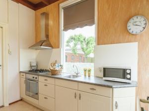 a kitchen with a sink and a clock on the wall at leisure retrete with costal nature in Wemeldinge