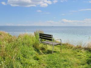 Årøsund8 person holiday home in Haderslev-By Traum的坐在靠近海洋的草地上的长凳 更多19张照片