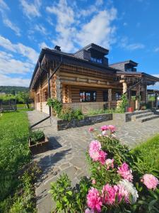 a log cabin with flowers in front of it at Bordeiul Legionarilor in Vatra Dornei