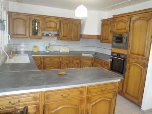 eine Küche mit Holzschränken und einer grauen Arbeitsplatte in der Unterkunft Sea View Family Escape in Denneville + 15 Fotos