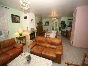 ein Wohnzimmer mit einem braunen Ledersofa und einer Küche in der Unterkunft Sea View Family Escape in Denneville