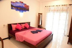 a bedroom with a bed with pink sheets and a window at Shells Villa Hikkaduwa in Hikkaduwa +28 photos
