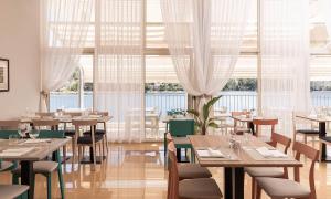 a restaurant with tables and chairs and windows at Aminess Younique Lume Hotel in Brna