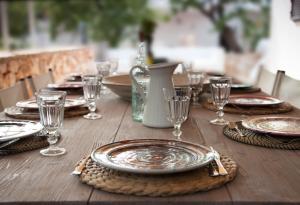 uma mesa de madeira com pratos e copos de vinho em Fikus - the Apulian B&B em Ceglie Messapica