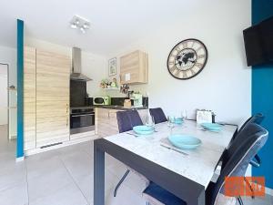 a kitchen with a table with chairs and a clock on the wall at La rose des vents in Wimereux