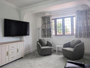 a living room with two chairs and a flat screen tv at Creek House with Hot Tub - Coming Soon in South Hayling