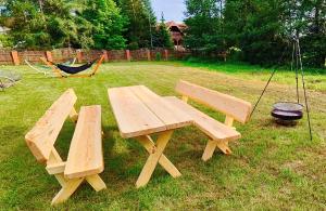 a wooden picnic table and swings in a yard at Mazurski oddech in Zgon