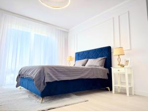 a blue bed in a white bedroom with a window at Boutique Apartment in Ploieşti