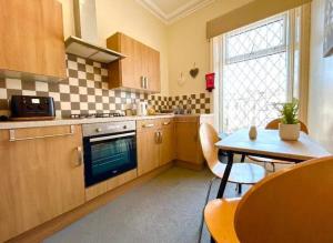 a kitchen with a table and a stove and a sink at The Copplehouse in Southport