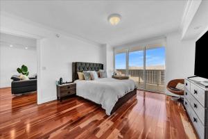 una camera bianca con un letto e una grande finestra di South City Suites a Hallandale Beach