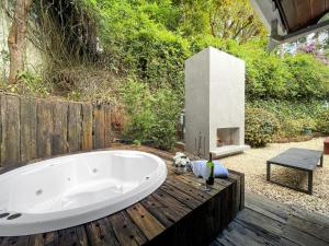 une baignoire sur une terrasse en bois avec une cheminée dans l'établissement 2 suítes Lareira Jacuzzi Churrasqueira, à Campos do Jordão