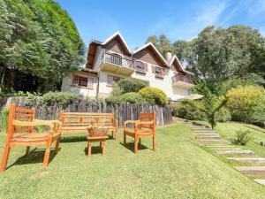a yard with two benches and a house at 1 suíte Jacuzzi Lareira Churrasqueira in Campos do Jordão
