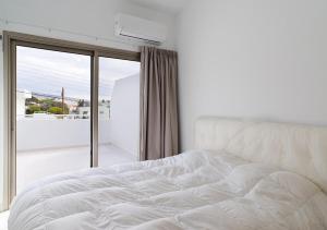 Una cama blanca en un dormitorio con ventana. en Columbia House, en Limassol 4 fotos más