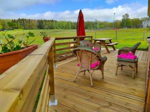 a wooden deck with chairs and a table and an umbrella at Clos du Bannet Family Escape in Givonne
