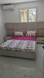 a bedroom with a bed with pillows and a window at Villa Ayem avec piscine à l'étage in Al Ḩārah al Kabīrah