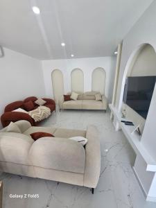 a living room with two couches and a television at Villa Ayem avec piscine à l'étage in Al Ḩārah al Kabīrah
