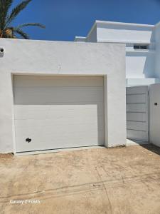 a white garage door on the side of a house at Villa Ayem avec piscine à l'étage in Al Ḩārah al Kabīrah
