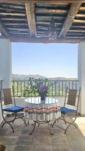 a table and chairs with a vase of flowers on it at Casa Rural La Chaparra - Apartamento Atalbéitar in Pitres