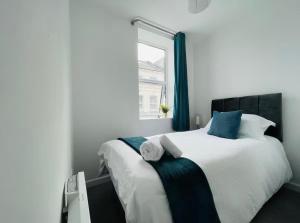a bedroom with a large white bed with blue accents at Spacious 2-Bed Apartment in Watford