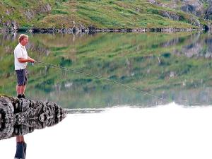 a man is standing in a lake holding a fishing line at 6 person holiday home in Nordli-By Traum in Holand