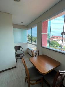 a dining room with a table and chairs and a window at Recanto Armação Pousada in Penha