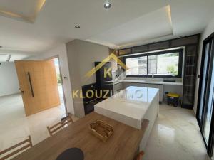 a living room with a white table and a kitchen at Maison haut standing a côté de la palage in Bizerte +9 photos