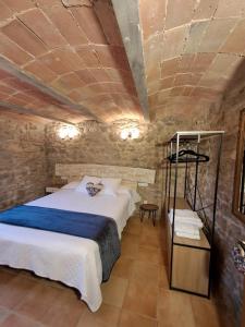a bedroom with a large bed and a stone wall at Rural Can Garriga in Palol de Revardit