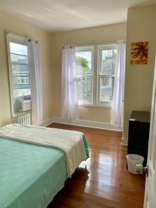 a bedroom with two windows and a bed and wooden floors at Tropical Oasis - Room 1 in Irvington