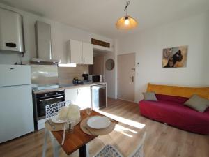a kitchen and a living room with a red couch at Appart 2 lits tv Wifi Parking Jardin in Montélimar