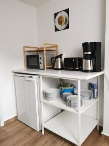 une étagère blanche avec des assiettes et un micro-ondes dans l'établissement City-Apartment Am Holzberg, à Wilkau-Haßlau 1 autre photo