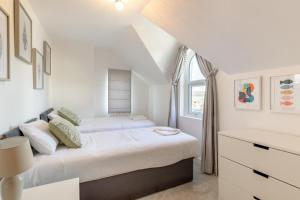 a white bedroom with a bed and a window at 2B Pen Y Bont in Abersoch