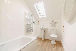 a bathroom with a white tub and a toilet and a sink at 2B Pen Y Bont in Abersoch +7 photos