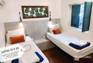 two beds in a small room with two windows at Hospedaria Rio in Rio de Janeiro