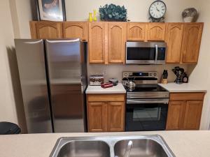 a kitchen with stainless steel appliances and wooden cabinets at 3 Bedroom Condo with Water Park & Fantastic Pool only Minutes To Walt Disney World's Front Gate!!! in Orlando +34 photos