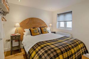 1 dormitorio con 1 cama con cabecero de madera y ventana en Ty-Llew Hideaway, en Abergavenny