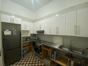 a kitchen with white cabinets and a stainless steel refrigerator at Patri House in Maputo